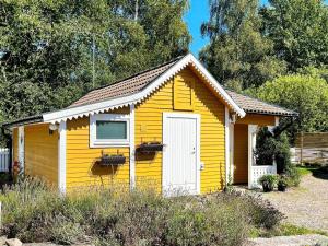 ein gelber Schuppen mit einem Fenster und einer Tür in der Unterkunft Holiday home Ronneby VI in Ronneby
