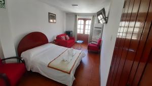 チャチャポヤスにあるCasa Kuelap Hostalのベッドルーム(白いベッド1台、赤い椅子付)