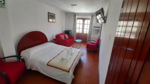 a bedroom with a white bed and red chairs at Casa Kuelap Hostal in Chachapoyas