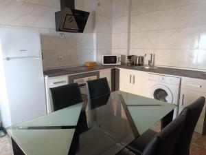 een keuken met een glazen tafel met stoelen en een wasmachine bij Apartamentos Luxury Puente de Triana in Sevilla