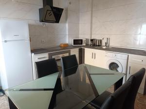 a kitchen with a glass table with chairs and a washing machine at Apartamentos Luxury Puente de Triana in Seville