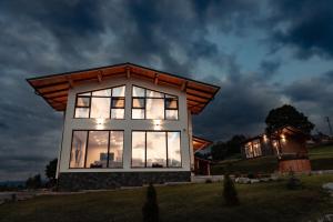 a house with a lit up window on a field at Watra Chalet in Vatra Dornei