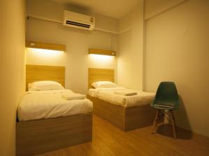 a room with two beds and a chair in it at Micro Hostel in Bangkok