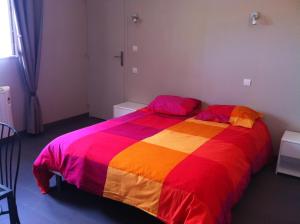 a bed with a colorful blanket on it in a room at Les Amandiers in Draguignan