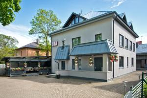 a large white house with flowers in a courtyard at Vila Vika in Palanga
