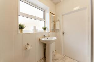 ein weißes Bad mit einem Waschbecken und einem Fenster in der Unterkunft Great Rooms in Plaistow in London