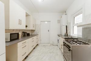 a kitchen with white cabinets and a stove top oven at Great Rooms in Plaistow - 147 in London
