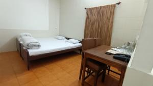 a small room with a bed and a table at Hotel Saluja in Siliguri
