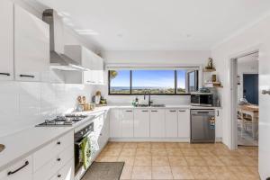 Una cocina con gabinetes blancos y una ventana grande. en Oceanfront Odyssey, en Portarlington