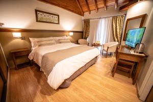 a bedroom with a bed and a desk and a television at Resort de montaña - La Comarca in Villa La Angostura