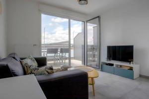 Una sala de estar con un sofá y un televisor de pantalla plana. en Le Nid des Romains - T2 neuf - Balcon - vue, en Annecy
