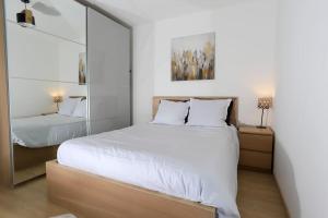 Un dormitorio con una gran cama blanca y un espejo. en Le Nid des Romains - T2 neuf - Balcon - vue, en Annecy