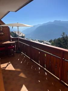 a balcony with a table and an umbrella at La casetta di Crans in Crans-Montana