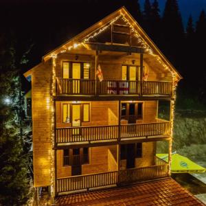 uma casa de madeira com luzes à noite em Panorama Bakhmaro em Chʼkhakoura