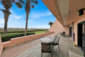 Un patio con mesa y sillas y palmeras. en Aegean 104 - Updated Aegean Gulf Front Property, en Destin