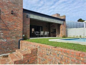 uma casa de tijolos com uma parede de tijolos e uma piscina em KARENINA'S Self-catering Accommodation em Riebeek-Kasteel