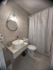 ein Badezimmer mit einem Waschbecken, einem WC und einem Spiegel in der Unterkunft Ama Boutique in Constanţa