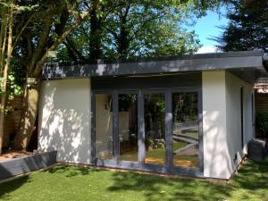 Una sala de jardín con puertas corredizas de vidrio. en Wychwood A Beautiful Country Style Bungalow, en Ash