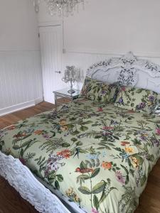 a bedroom with a bed with a floral bedspread at Wychwood A Beautiful Country Style Bungalow in Ash