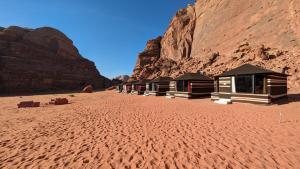 una fila di capanne nel deserto vicino a una montagna di WhyDesert Camp & Tours a Wadi Rum