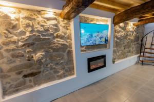 sala de estar con pared de piedra y chimenea en Casa Luna Rural Con Piscina y Jardín, en Ourense