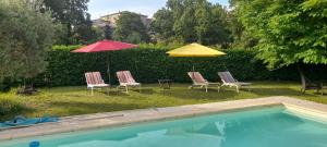 three chairs and umbrellas next to a swimming pool at La picholine chambre paons in Courry