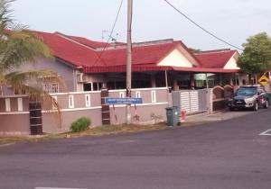 ein Haus mit rotem Dach und einem Auto vor dem Haus in der Unterkunft Homestay Permai Inn in Temerloh