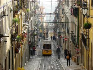 un tranvía amarillo conduciendo por una calle con edificios en Apartamento Bairro Alto, en Lisboa