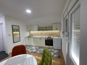 ソコバニャにあるApartman La Vista Sokobanjaの白いキャビネットとテーブルと椅子のあるキッチン