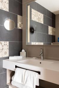 ein Badezimmer mit einem weißen Waschbecken und einem Spiegel in der Unterkunft Hilton Garden Inn Bordeaux Centre in Bordeaux