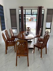a dining room with a wooden table and chairs at Homestay PCB Villa MamaKaya in Kota Bharu