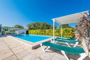 a swimming pool with two green lounge chairs and an umbrella at Villa Volentina in Port de Pollensa