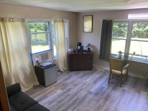 a living room with a couch and a desk and two windows at Heart of the Berkshires Motel in Pittsfield