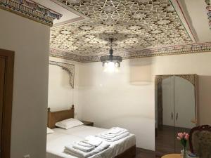 1 dormitorio con 1 cama con toallas en Tasvir Hotel, en Bukhara