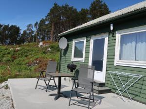 einen Tisch und Stühle auf einer Terrasse neben einem grünen Haus in der Unterkunft Holiday Home Sognesjön - FJS128 by Interhome in Bø