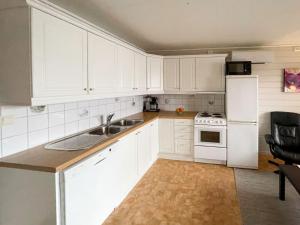 uma cozinha com armários brancos, um lavatório e um frigorífico em Apartment Bakkafall - FJS078 by Interhome em Svortevik