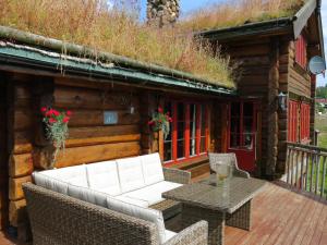 a patio with wicker chairs and a table in front of a cabin at Chalet Lindefjeldbu - SOW144 by Interhome in Fossdal