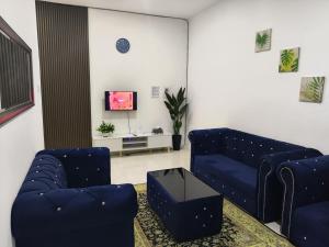 a living room with two blue couches and a tv at Amisya Homestay in Kampung Raja