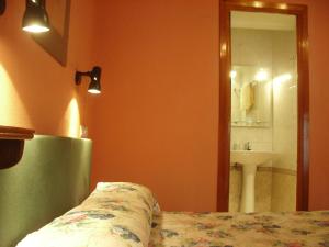 a bathroom with a bed and a sink and a mirror at Hospedaje Senda del Huerna in Campomanes