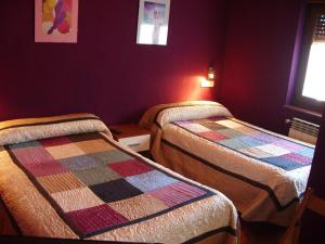 2 camas en una habitación con paredes moradas en Hospedaje Senda del Huerna, en Campomanes
