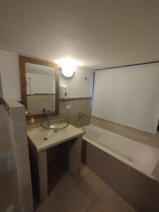 ein Badezimmer mit einem Waschbecken, einer Badewanne und einem Spiegel in der Unterkunft Boutique Portón De Granada in Cali