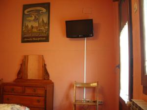 a bedroom with a tv on the wall and a chair at Hospedaje Senda del Huerna in Campomanes