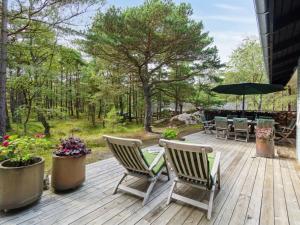 a wooden deck with chairs and an umbrella at Holiday Home Alita - 300m from the sea in Bornholm by Interhome in Vester Sømarken