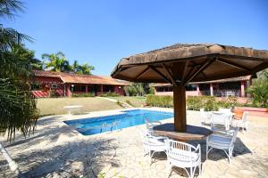 a table and chairs under an umbrella next to a pool at Sitio Agua Doce in Santa Branca