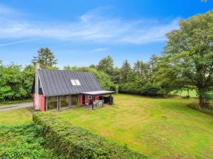 czerwony dom z czarnym dachem na trawniku w obiekcie Holiday Home Thana - 8km from the sea in Bornholm by Interhome w mieście Gudhjem