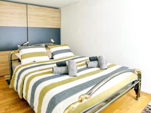 een slaapkamer met een bed met gestreepte lakens en kussens bij Apartment Orya by Interhome in Interlaken