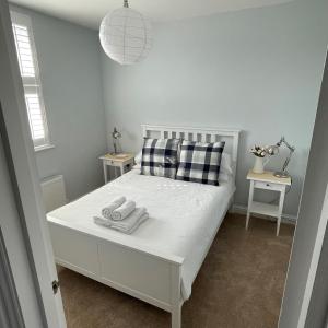 a bedroom with a white bed with two towels on it at Swanage Bay Coastal Apartment in Swanage