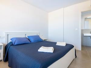ein Schlafzimmer mit einem blauen Bett mit zwei blauen Kissen in der Unterkunft Apartment Gran Canet by Interhome in Canet d'en Berenguer