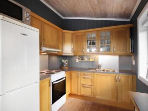 cocina con armarios de madera y nevera blanca en Holiday Home Havbu - FJS166 by Interhome, en Korssund