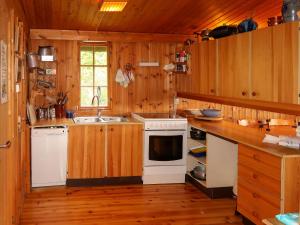 cocina con armarios de madera y horno de fogón blanco en Chalet Trefall - FJH520 by Interhome, en Gausvik